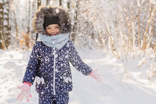 Girl play snowballs and have fun in winter forest. Running and moving. Happy childhood. Winter holiday. Deep snow. Girls. Warm clothes. Throw snow