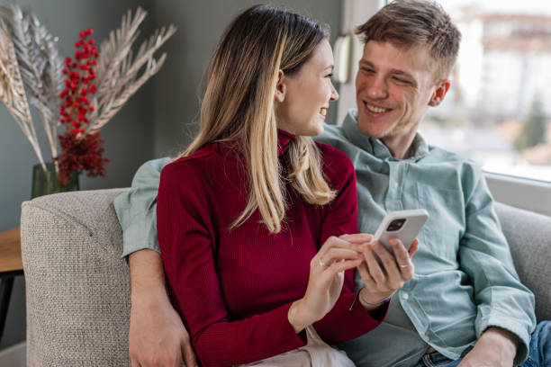 istock Young couple using smartphone in the living room 1447229142