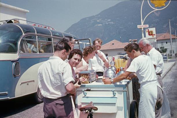 Merano, South Tyrol, Italy, 1956. Tourists take advantage of a fuel break to buy an ice cream. Also: ice cream vendor with his bicycle ice cream cart.