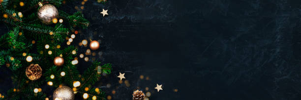Banner with Christmas tree branches, golden baubles and pine cones on black background with Christmas bokeh lights. New Year concept. Top view, copy space