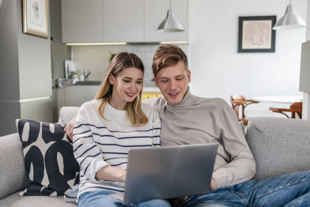 istock Young couple smiling and looking at the laptop 1447231254
