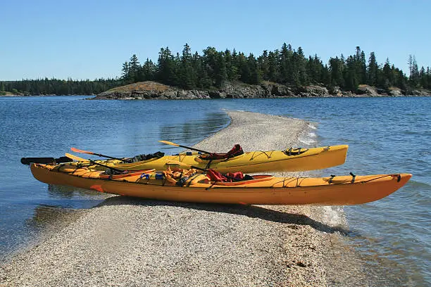 Kayaks sitting on a sand bar along the Maine coast.