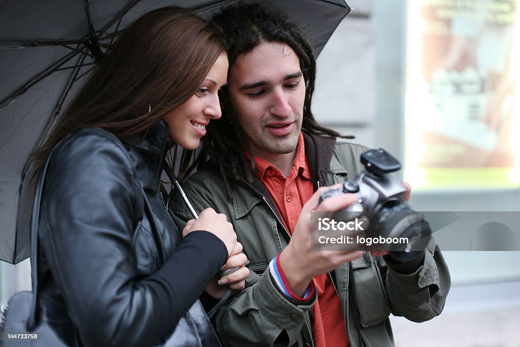Młoda para patrzy w kamerę cyfrową, Uśmiechać się - Zbiór zdjęć royalty-free (Aparat fotograficzny)