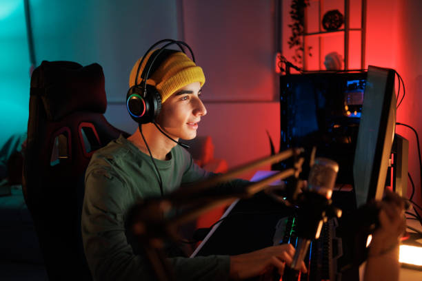 Teenage gaming streamer playing video game in his room stock photo