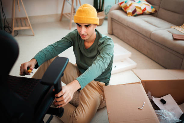 istock Young casually clothed teenager assembling computer chair in his room 1447239833