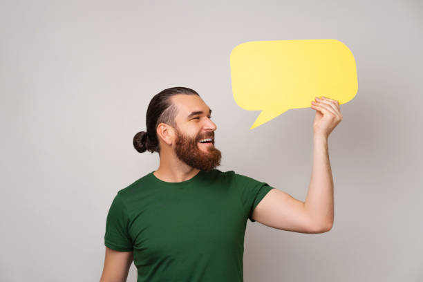 istock Wide smiling bearded man is holding a yellow bubble speech beside his head. 1447240410