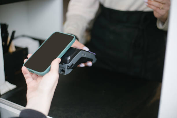 istock Close-up view of girl using Apple Pay on a iphone paying for purchases 1447241365