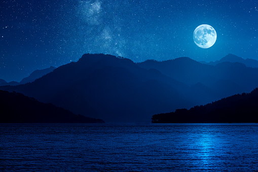 Rising moon over mountains against starry starry night