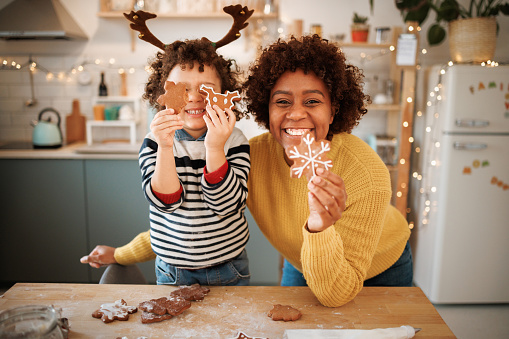 Portrait of mother and son with gingerbread cookies in a domestic kitchen