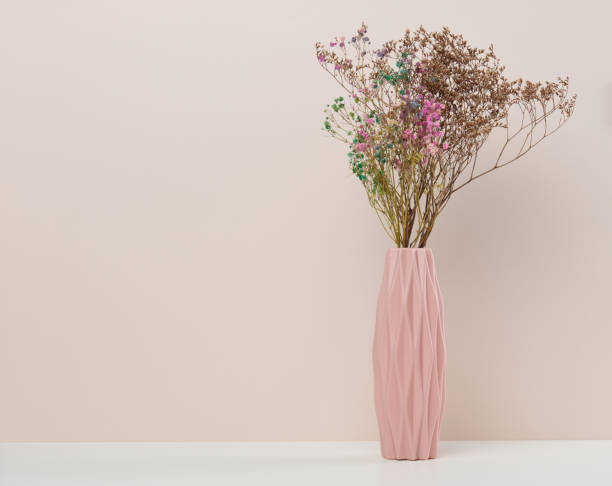 istock Pink ceramic vase with dry flowers on a white table 1447246567
