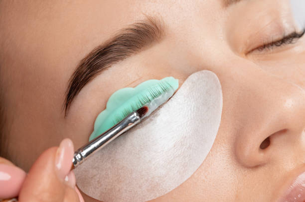 make-up artist makes the procedure of lamination and dyeing of eyelashes to a beautiful woman in a beauty salon. eyelash extensions. eyelash lifting - oppakken stockfoto's en -beelden