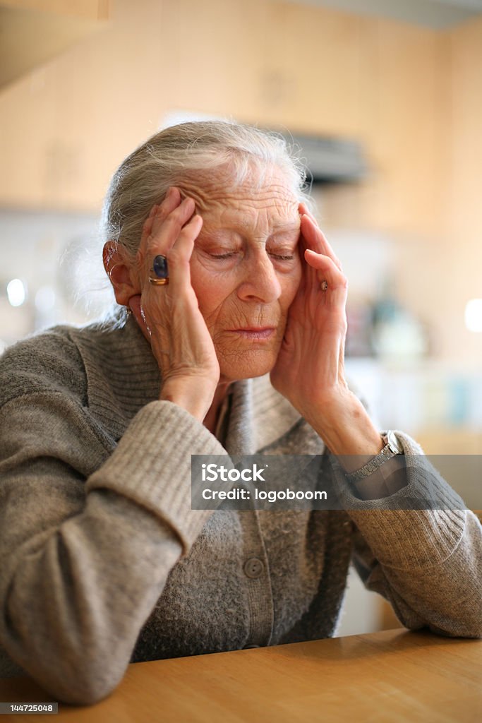 Senior lady with head in hands, eyes closed. Senior woman relaxing to end headache. Shallow DOF. 70-79 Years Stock Photo