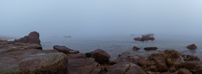 Panorama of rock formation at the sea in the fog on a hazy mystic autumn morning in Sillon de Talbert area, Brittany, France