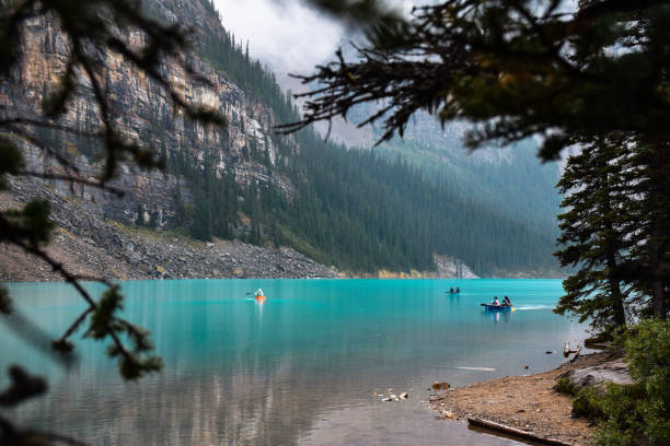 istock Tiny people in canoes on a lake surrounded by mountains 1447254735
