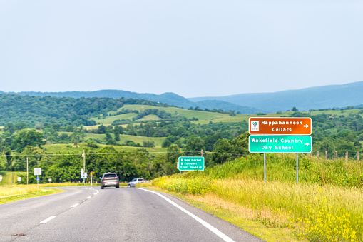 Huntly, USA - June 1, 2019: Rappahannock county highway route 522 road sigs for winery, Wakefield country day care by rolling hills rural background