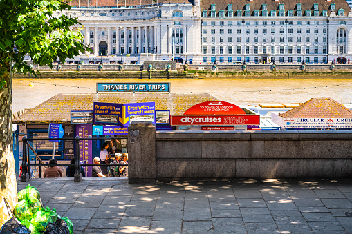 London, United Kingdom - June 22, 2018: Thames River Victoria embankment sign for cruise boat trips with kiosks selling tickets for people in summer