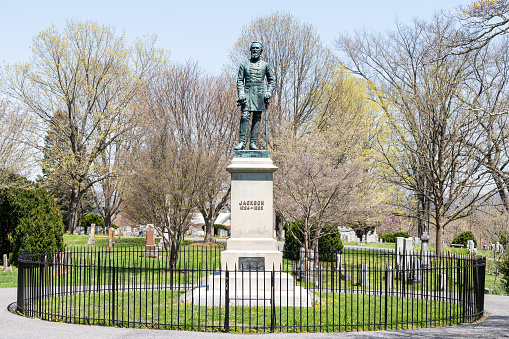 Lexington, USA - April 18, 2018: Stonewall Jackson Memorial Cemetery with bronze statue of standing general at gravesite in Virginia town or city with circle round cast iron fence