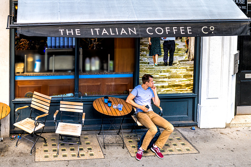 London, United Kingdom - June 22, 2018: High angle view on man sitting at Italian coffee house shop of Caffe Nero on Queen Victoria street sidewalk