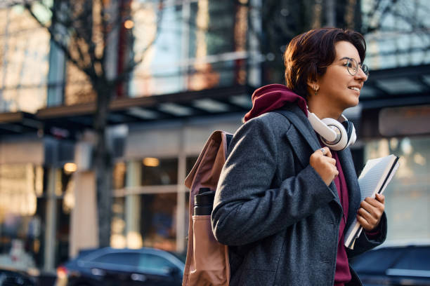 istock Young happy woman with backpack and notebooks going on a lecture at the university. 1447258318