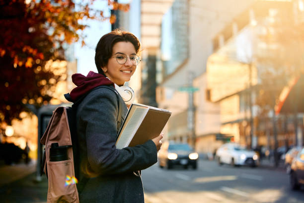 feliz estudiante universitaria en la ciudad mirando a la cámara. - city street audio fotografías e imágenes de stock