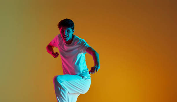 istock man dancing on yellow background. Neon lighting 1447262775
