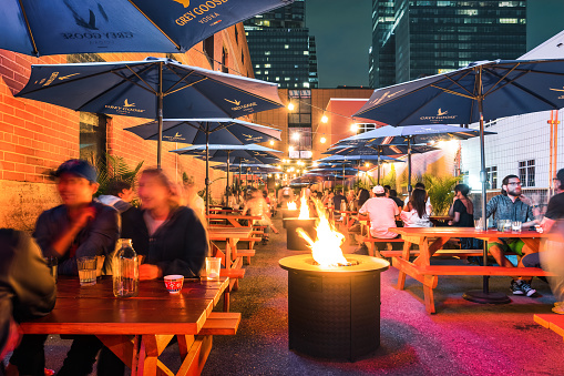 People enjoy the patio of a bar restaurant in downtown Edmonton, Alberta, Canada in the evening, as seen from the sidewalk.