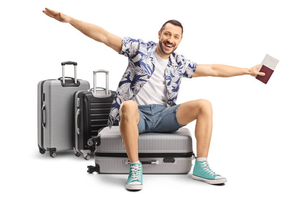 Turista maschio seduto su una valigia e allargando le braccia per volare - foto stock