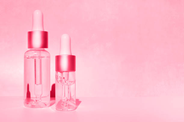istock Dropper bottles with cosmetic oil on a pink background. Side view, space for text. Demonstrating the colors of 2023 Viva Magenta. 1447270051