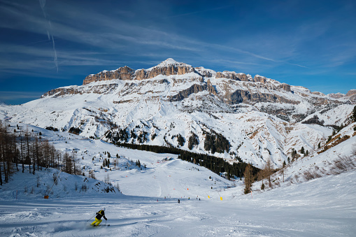 Canazei, Italy - February 16, 2019: View of a ski resort piste with people skiing in Dolomites in Italy. Ski area Arabba. Arabba, Italy