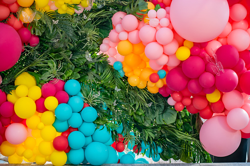 Balloons and plants are aranged on a backdrop for photos