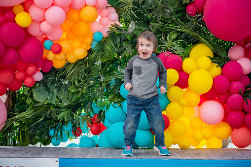 The 4 year old boy is checking out this balloon display at the greenhouse. He is very excited and moving around a lot.