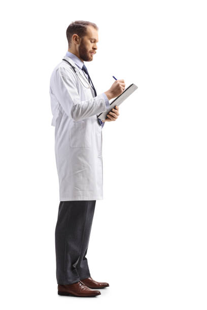 Full length profile shot of a male doctor standing and writing a document Full length profile shot of a male doctor standing and writing a document isolated on white background man standing profile stock pictures, royalty-free photos & images