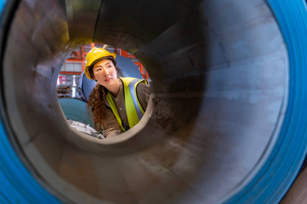 istock Asian engineer worker is examining the stainless galvanized metal sheet roll inside the warehouse factory for roofing industry concept 1447276408