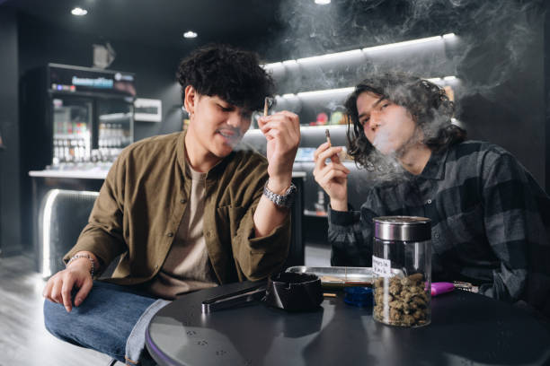 istock Young hipster guy smoking marijuana joint while relaxing with friend. 1447281547