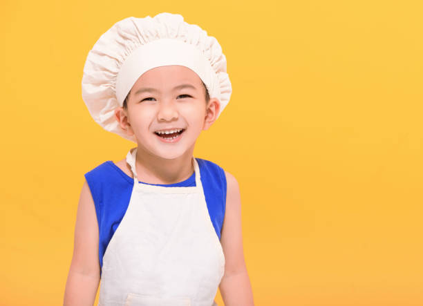 istock Happy kid in chef uniform  on yellow background 1447289857