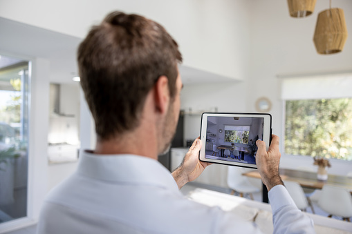 Real estate agent taking pictures of a house using a tablet computer - real estate concepts