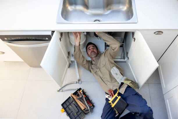 Plumber fixing a leak in the sink in the kitchen