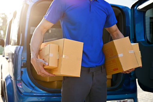 Close up view of professional delivery man holding packages, preparing to customer