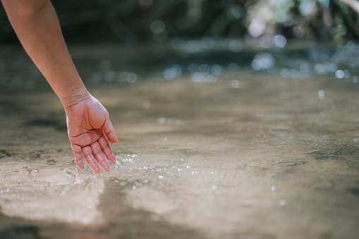 close up Asian chinese Woman feeling and touching the clear natural river water