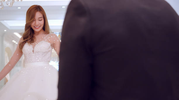 istock Young Asian couple trying on wedding dresses in wedding studio. 1447300225