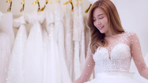 istock Young Asian bride trying on wedding dresses in wedding studio. 1447300244