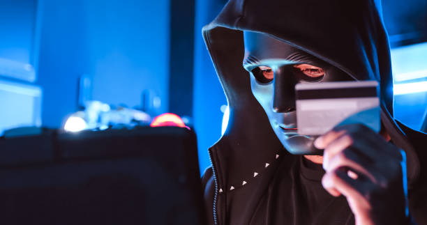 istock A hacker wearing a mask to cover his face is using computer to hack data to get ransom from victims. 1447300584