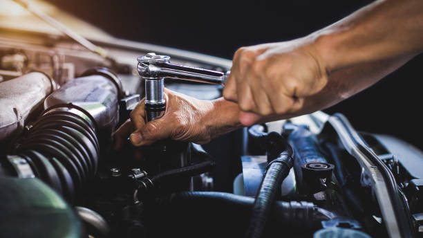 Car mechanic working on car engine, car maintenance concept.