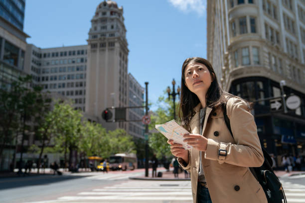 istock curious asian Japanese girl visitor looking around city with guide map while exploring downtown san Francisco in California usa near triangular office building on sunny day 1447301590