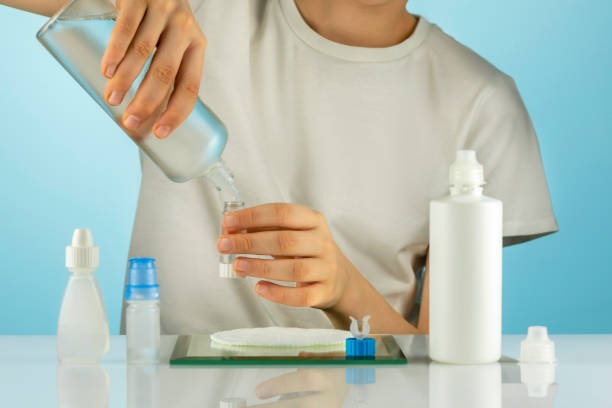 Boy clean contact lenses with cleansing solution on a blue background