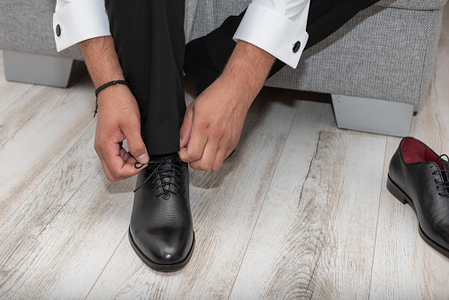 the groom closes his black shoes on the wedding day