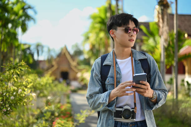 istock Man traveler using smart phone while standing outdoor with beautiful sky and buddhist temples on background. 1447306652
