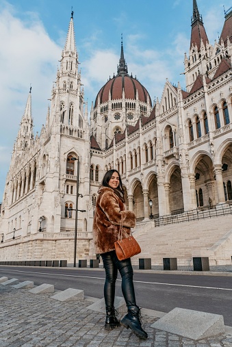 A vertical view of A woman posing before the Hungarian Parliament Building in Budapest