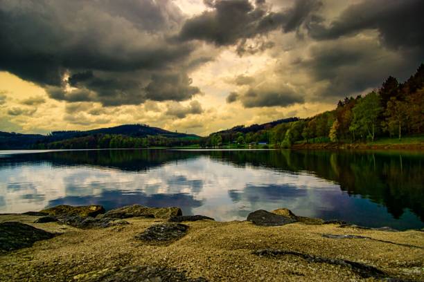 istock Landscape sunset scene reflecting on lake water with green trees around 1447312164