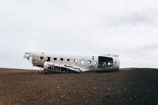 An old abandoned white airplane on the field with white sky in the background